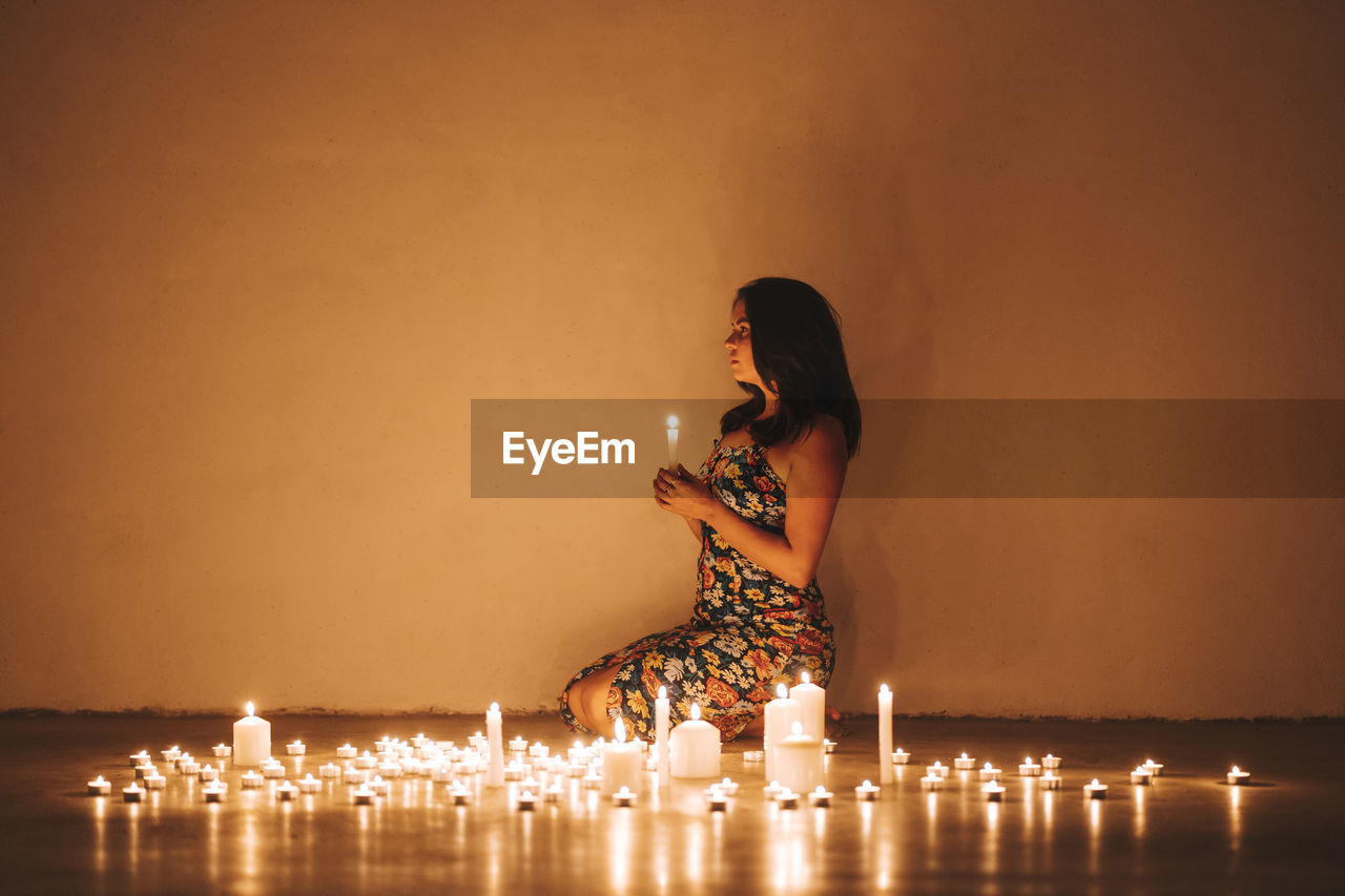 Woman with illuminated candles in living room at home