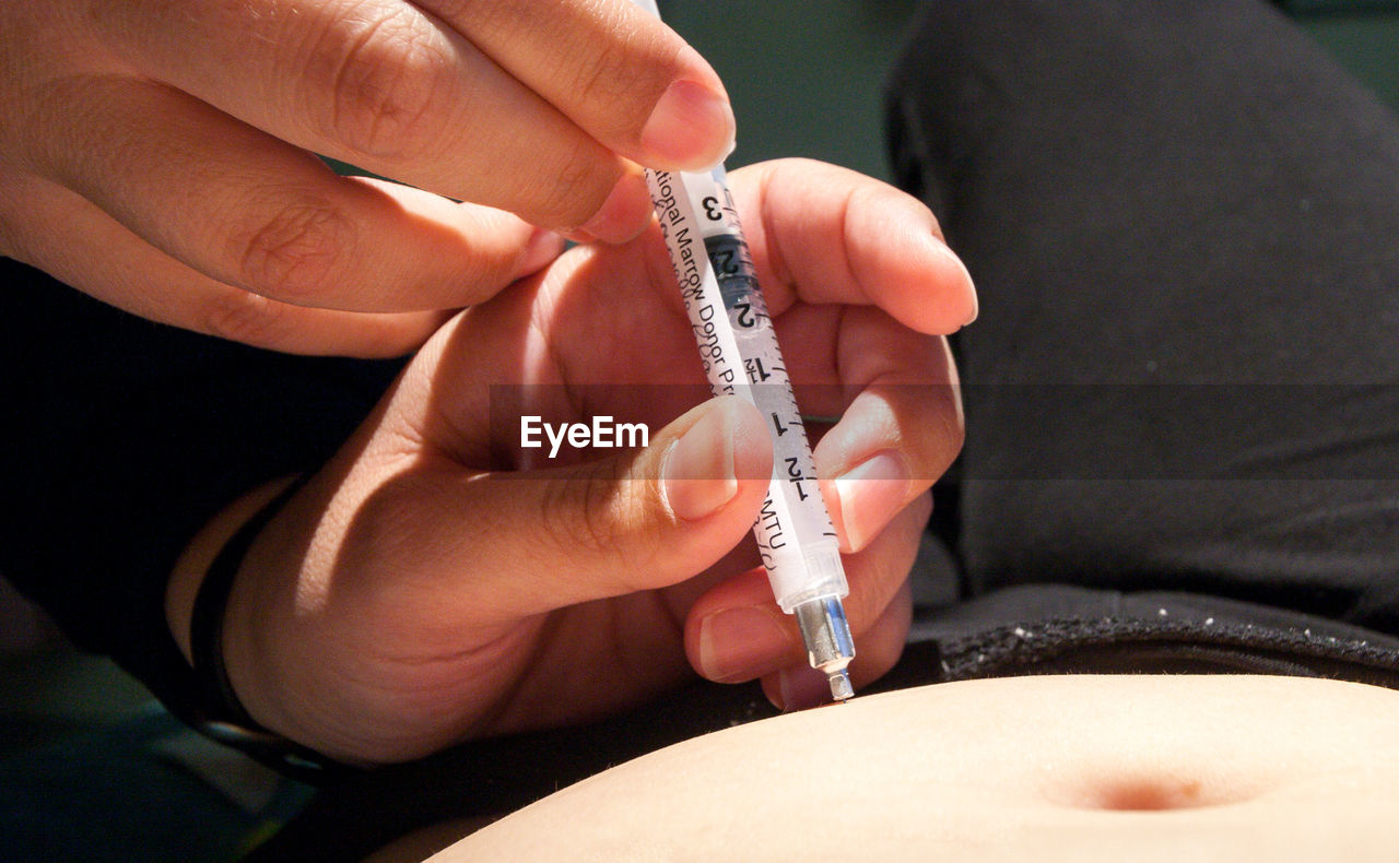 Cropped hands of nurse injecting patient at hospital