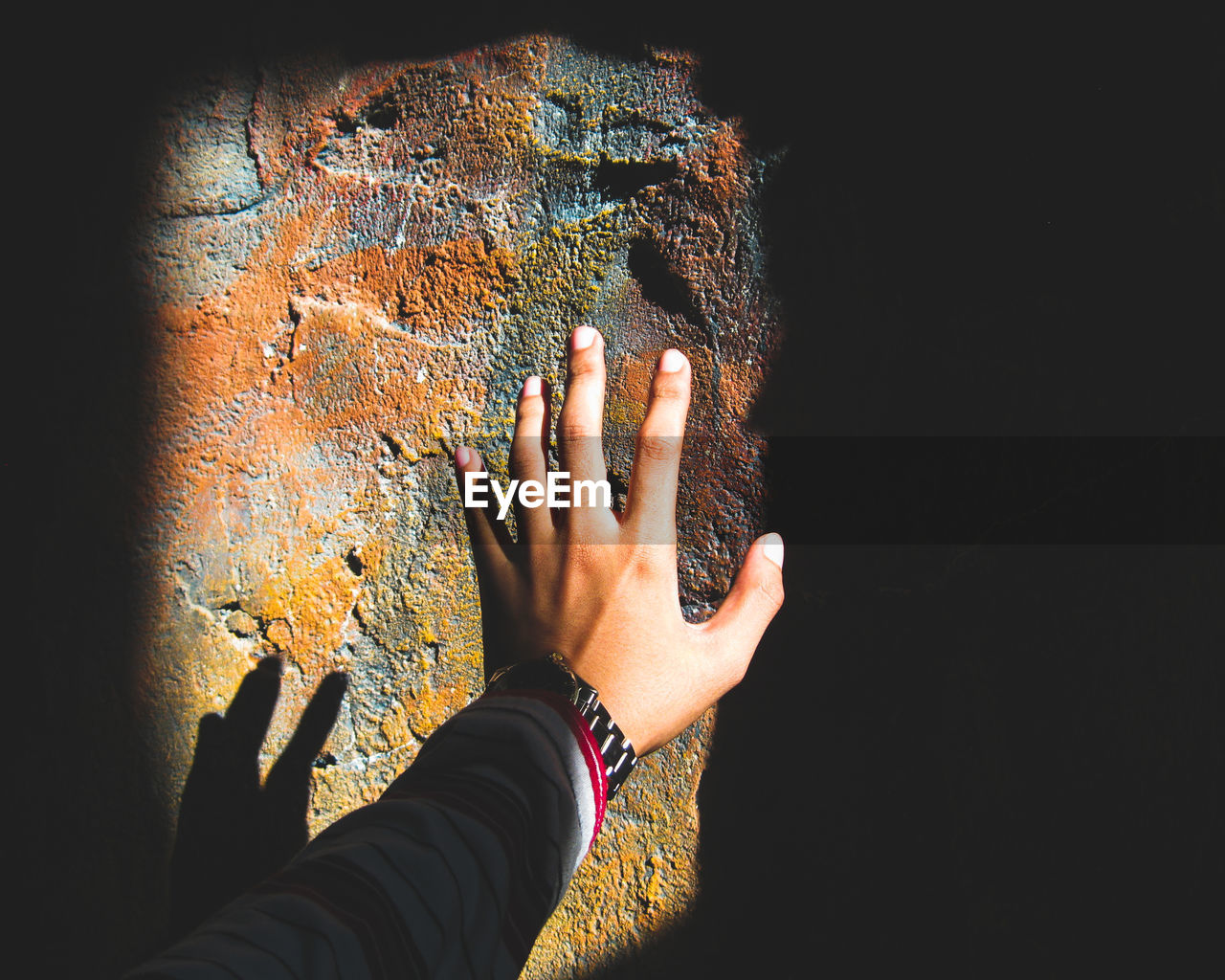 Cropped hand of woman reaching wall