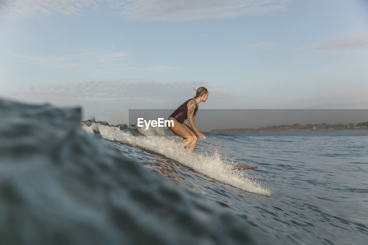 Young woman surfing at sunrise