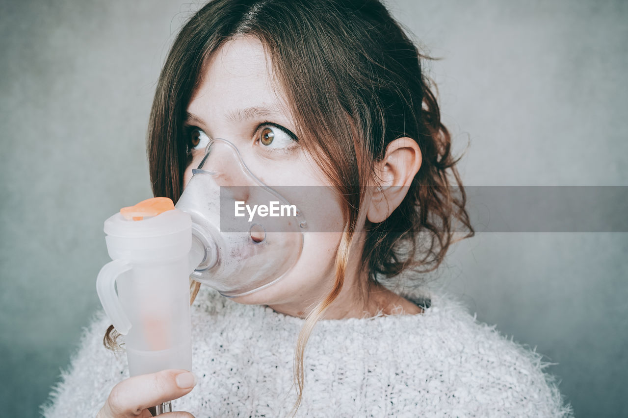 PORTRAIT OF A YOUNG WOMAN DRINKING WATER FROM PIPE