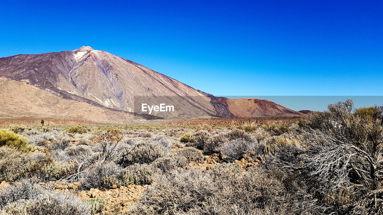 Scenic view of rocky mountains against clear blue sky