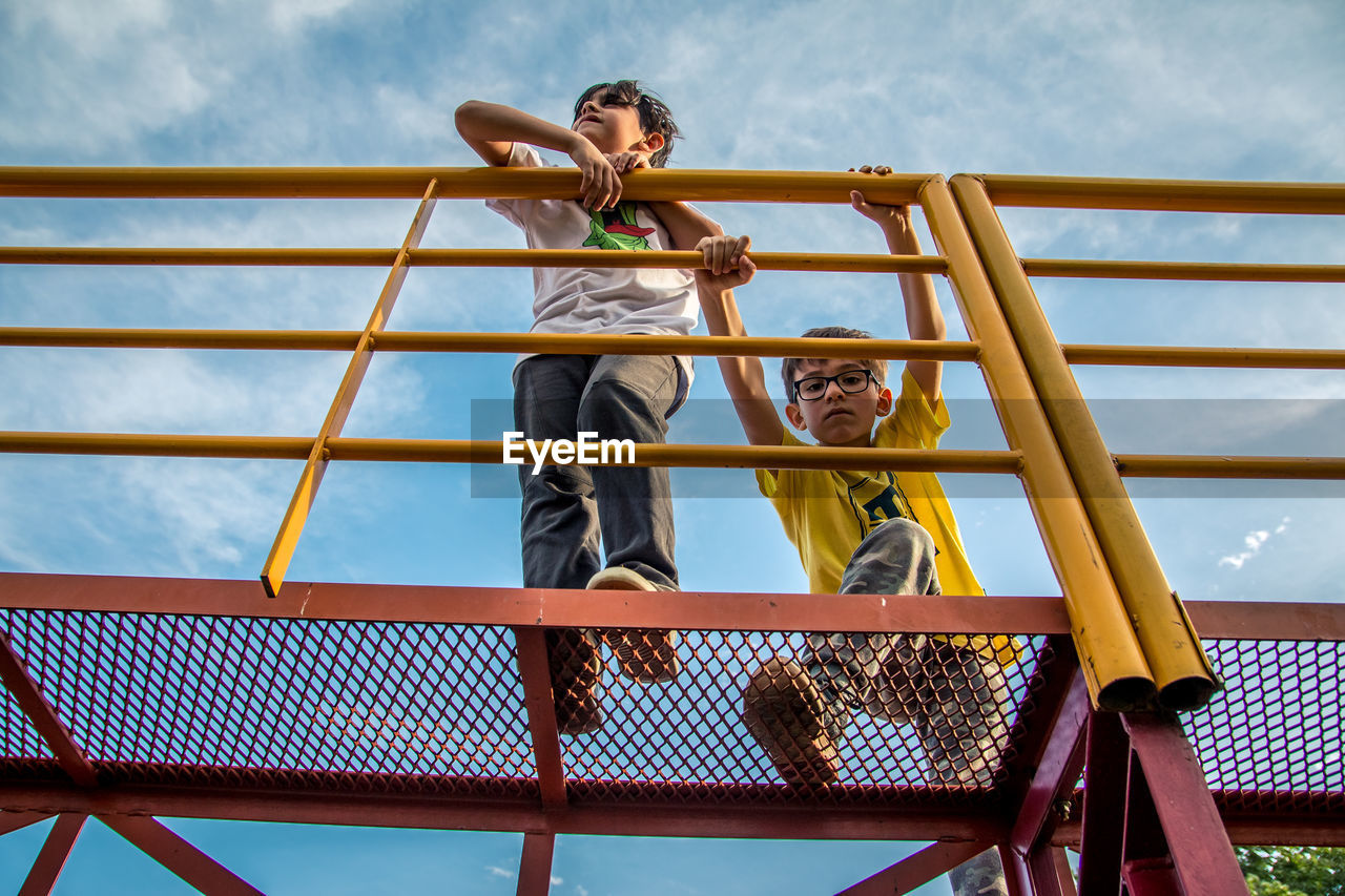 Low angle view of kids at playground against sky