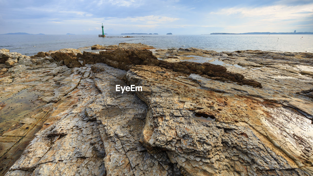 ROCK FORMATION ON SHORE AGAINST SKY