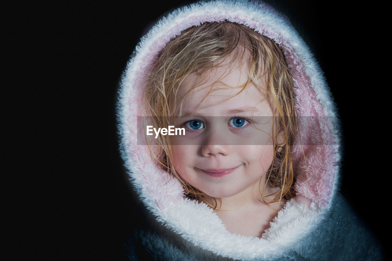 Close-up portrait of a cute girl against black background