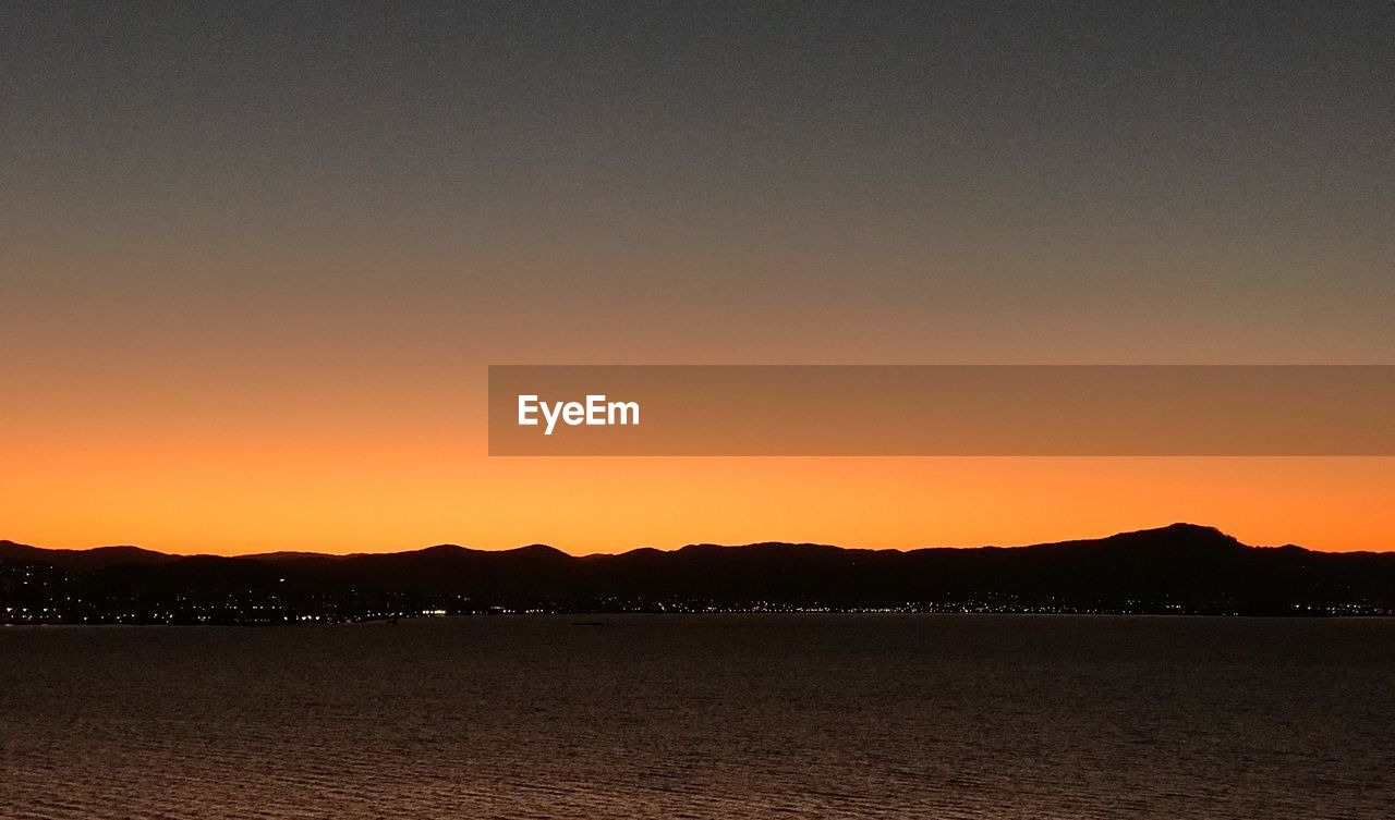 SCENIC VIEW OF SEA AGAINST ORANGE SKY DURING SUNSET