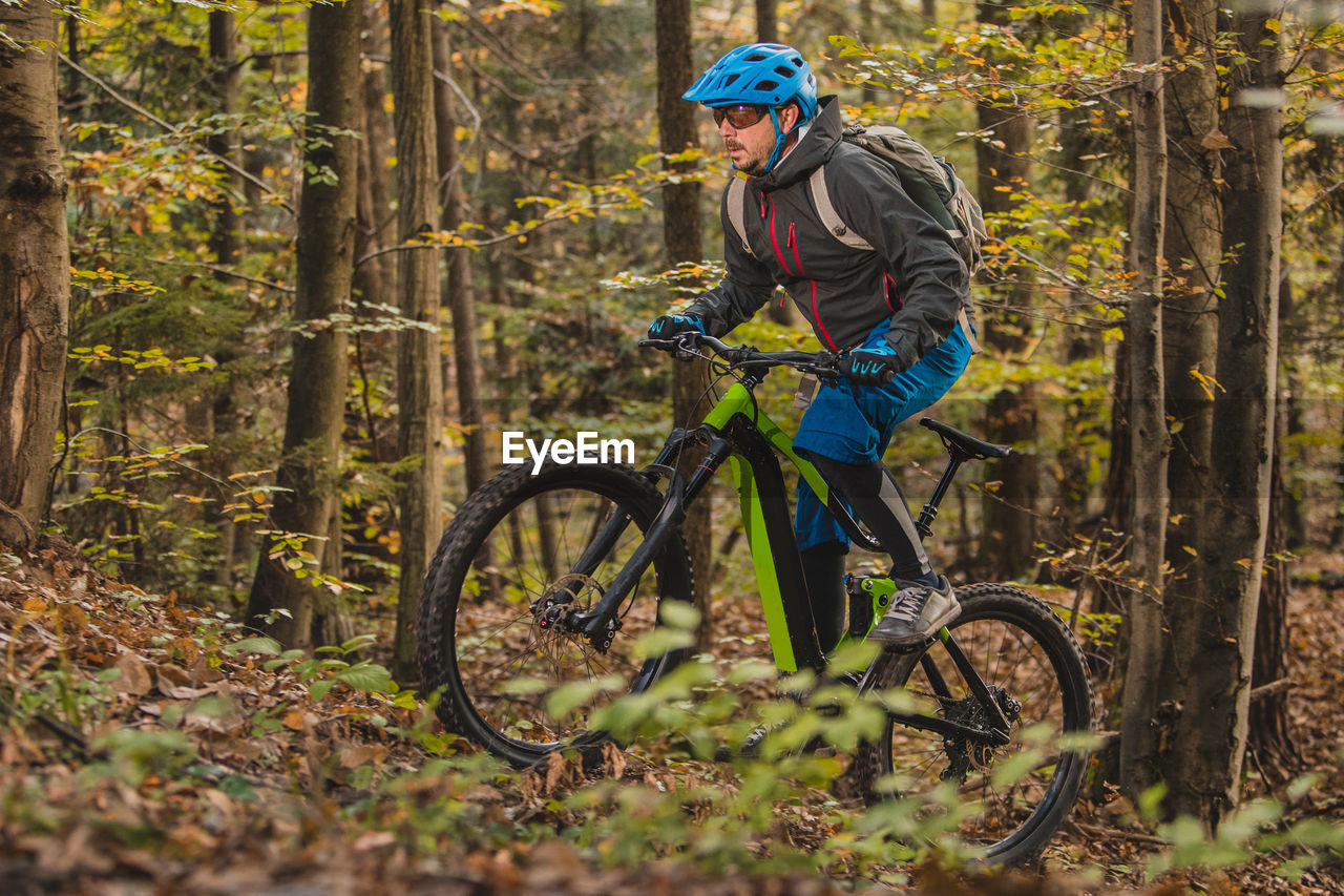 MAN RIDING BICYCLE ON FOREST