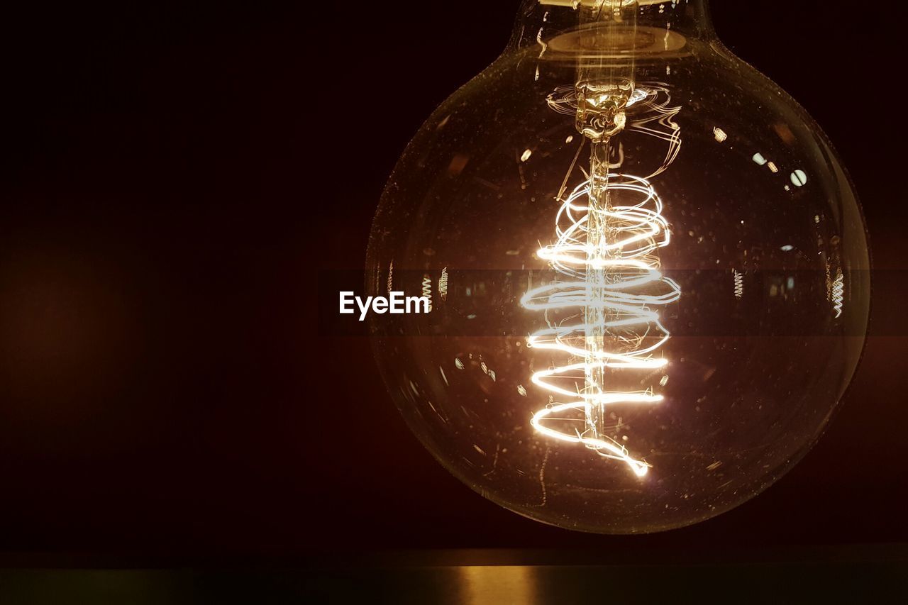 Close-up of illuminated light bulb against black background