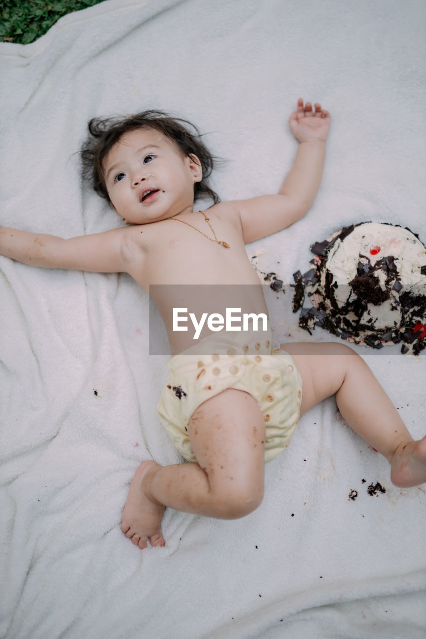 Portrait of shirtless baby boy lying on bed