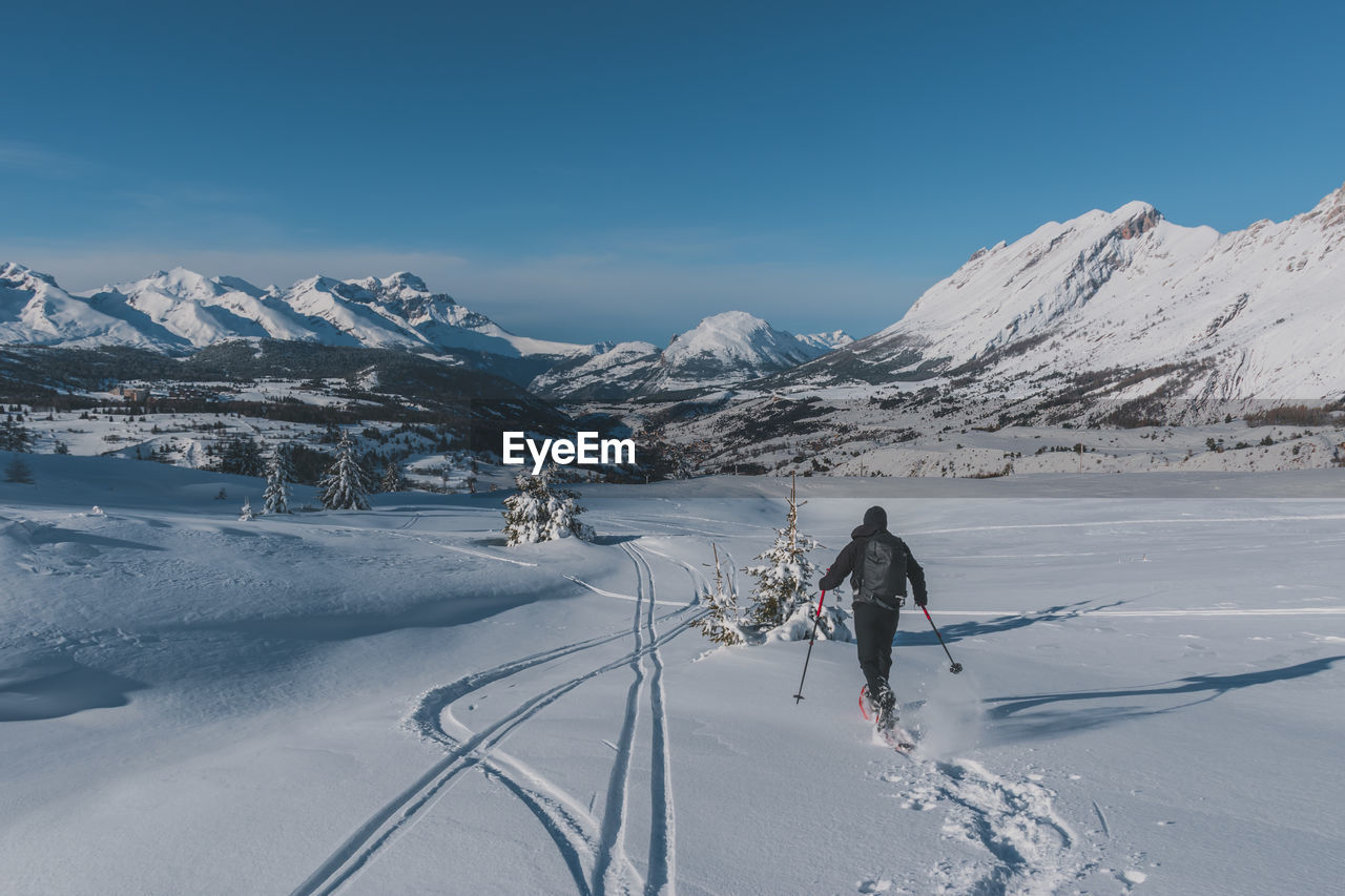 An unrecognizable male hiker wearing snowshoes running in the french alps on a cold winter day