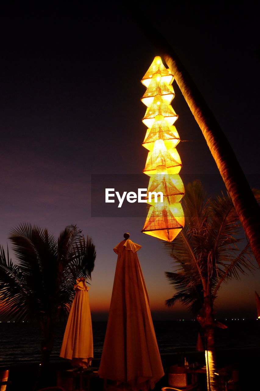 LOW ANGLE VIEW OF ILLUMINATED CHRISTMAS TREE AGAINST SKY