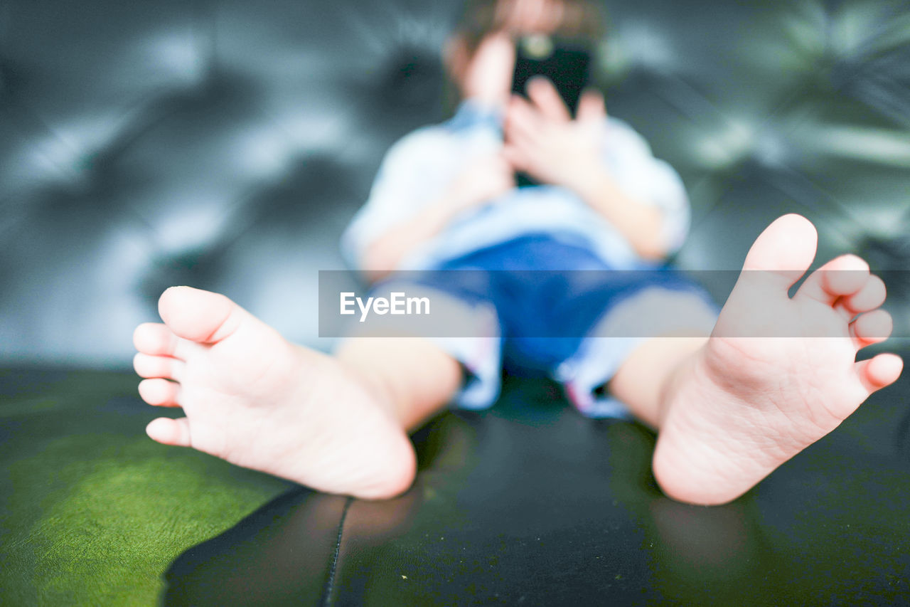 Girl using mobile phone while sitting on sofa