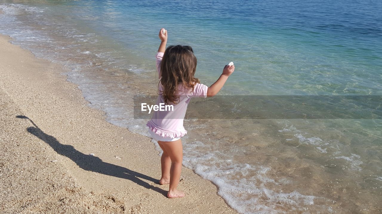 Rear view of girl standing at beach