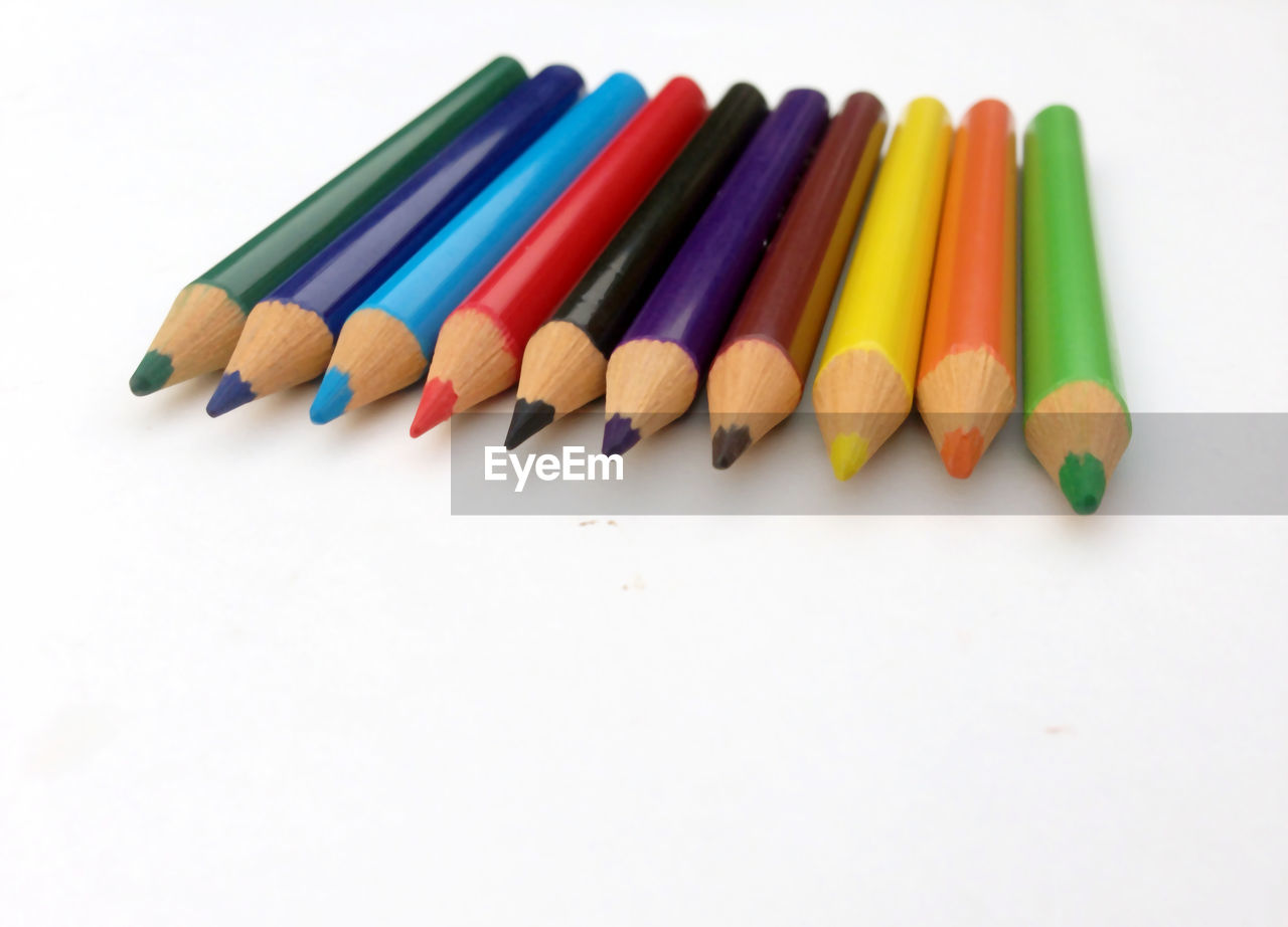 HIGH ANGLE VIEW OF COLORED PENCILS OVER WHITE BACKGROUND