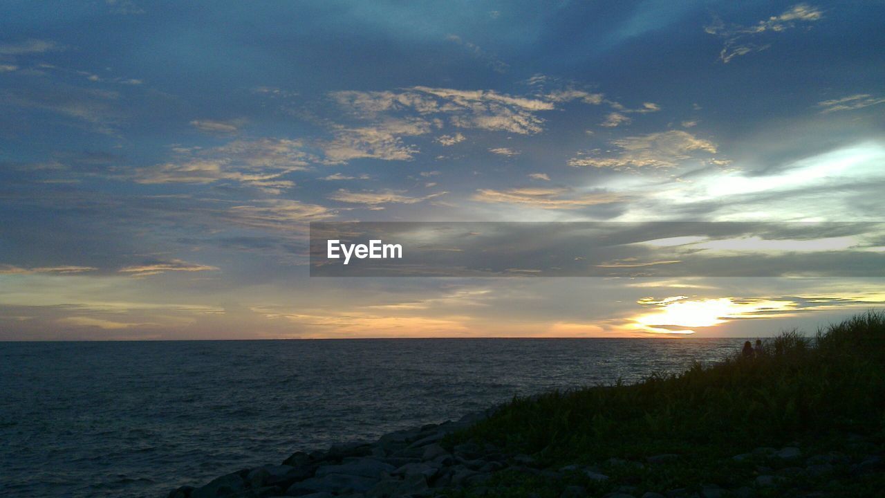 SCENIC VIEW OF CALM SEA AT SUNSET