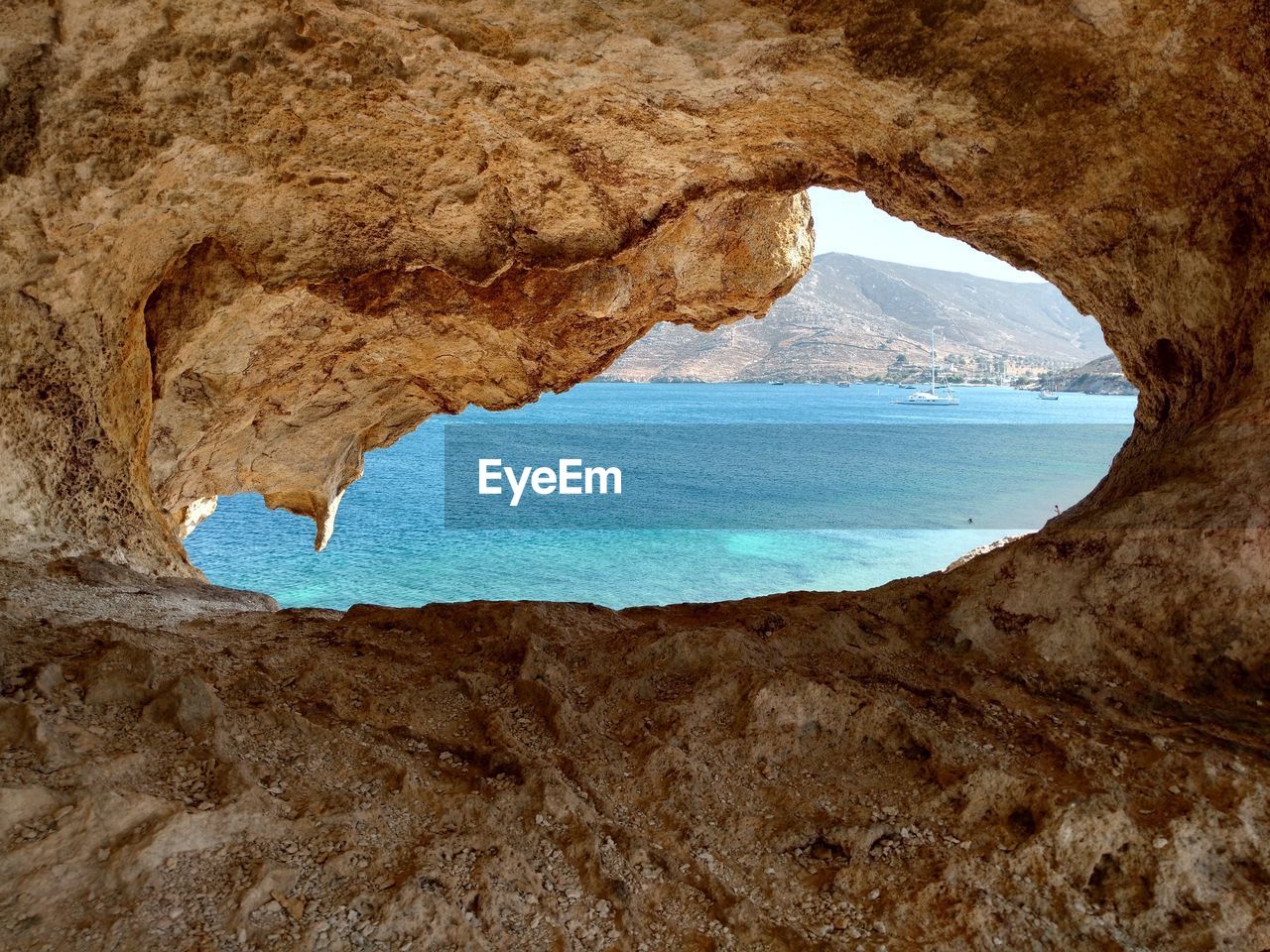 Scenic view of beach against clear sky seen from cave