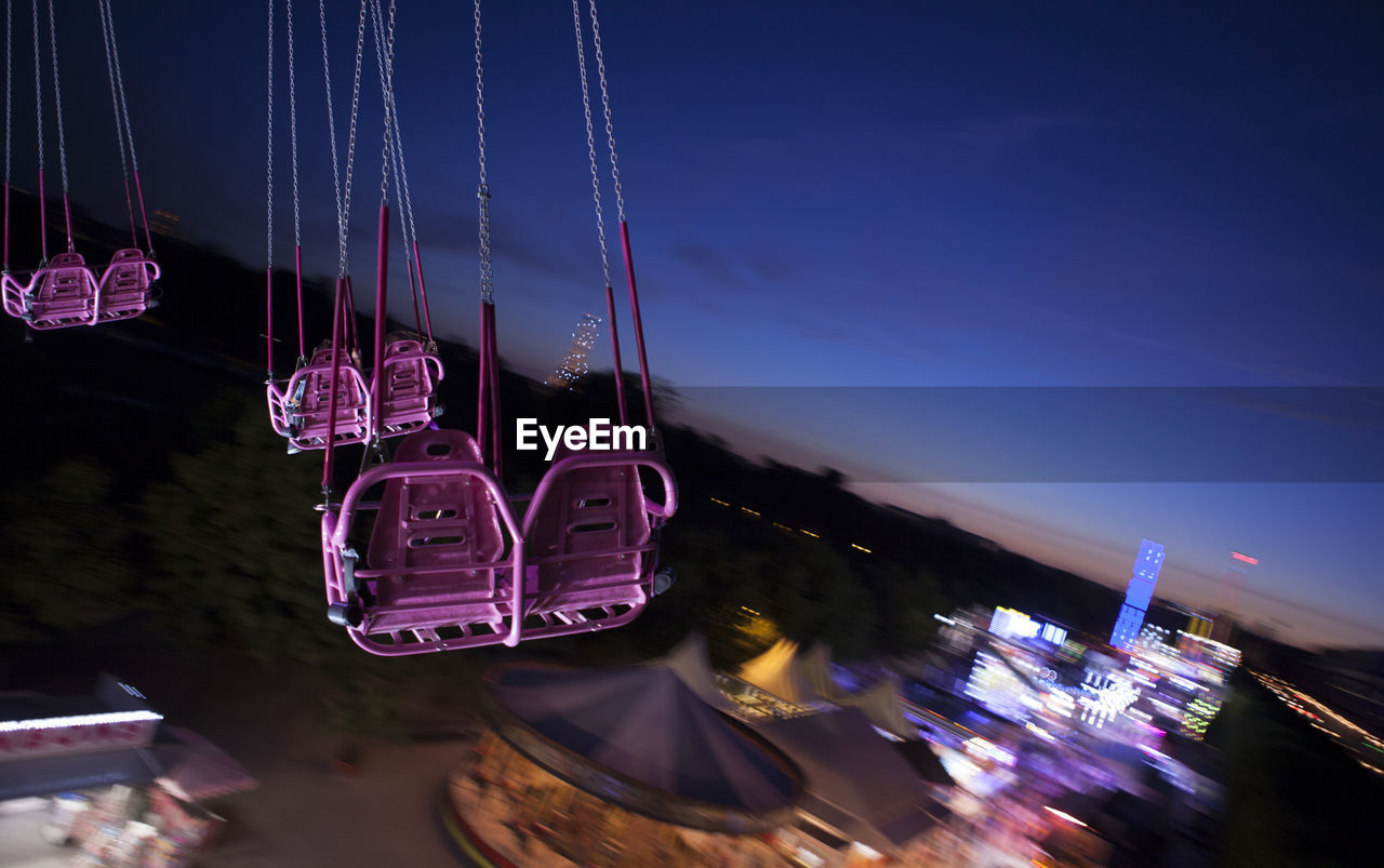 Chain swing ride spinning against sky at dusk