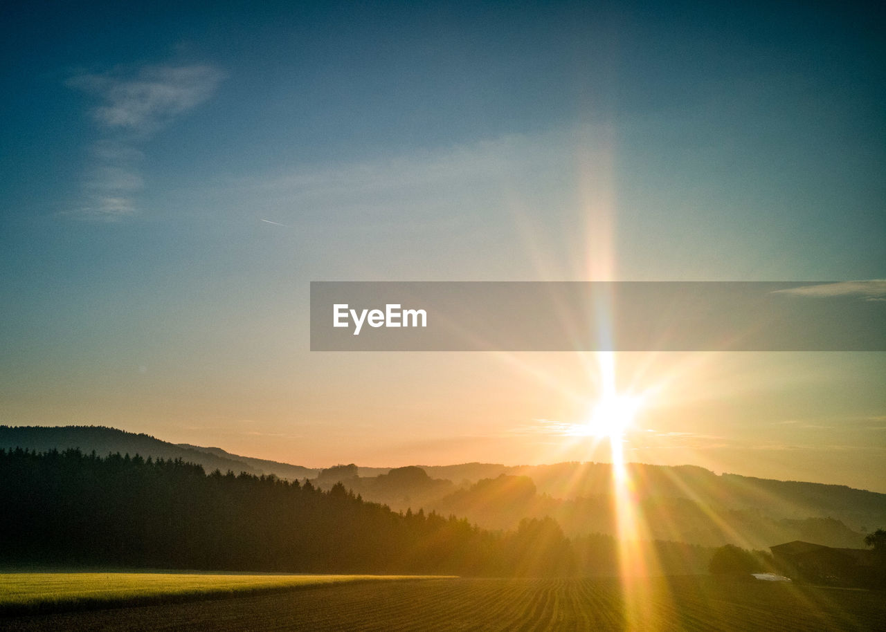 Scenic view of landscape and mountains against sky during sunrise