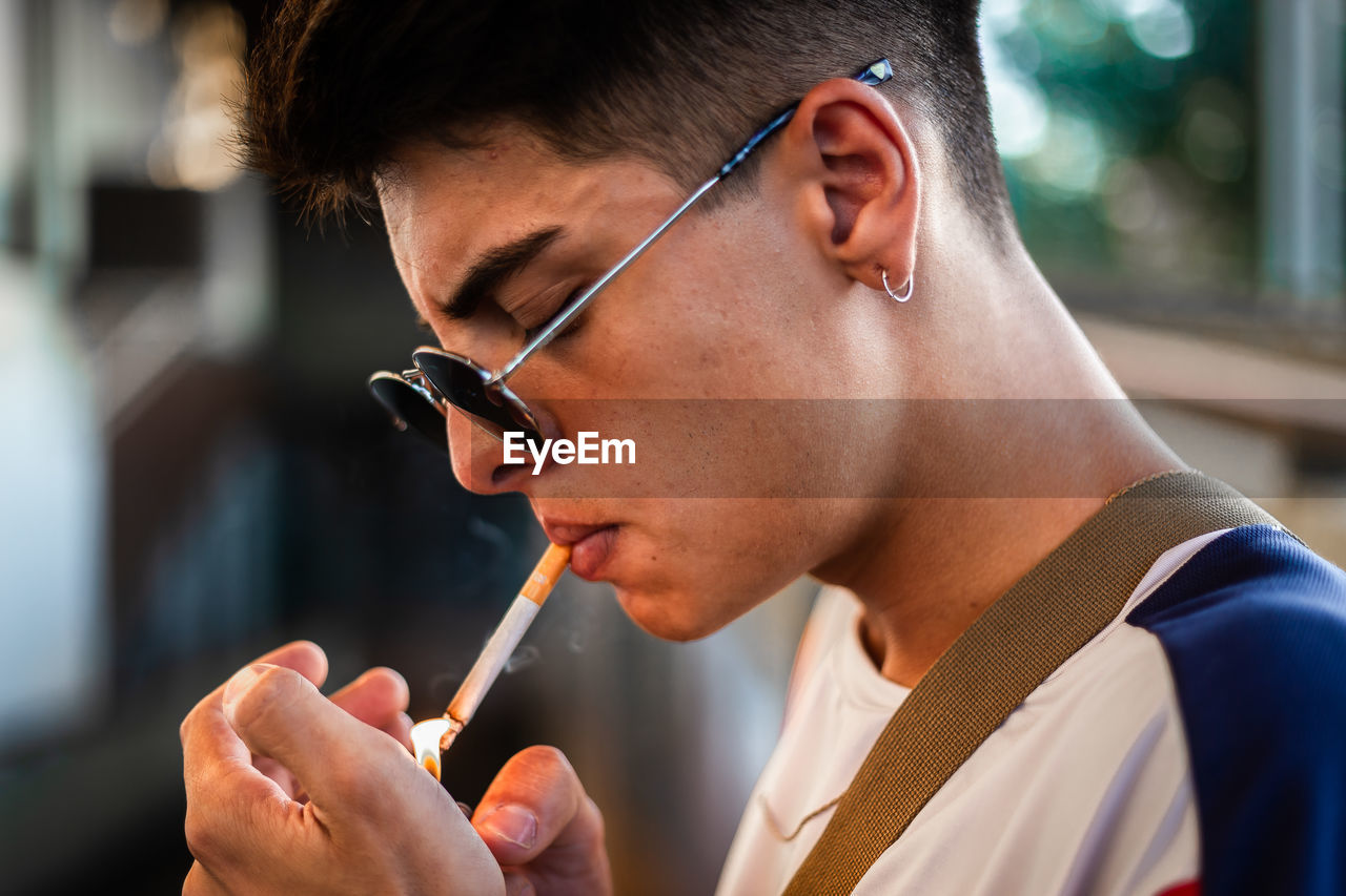 A young man wearing sunglasses and smoking a cigarette