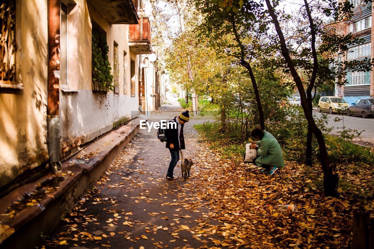 PEOPLE WALKING ON STREET AMIDST TREES