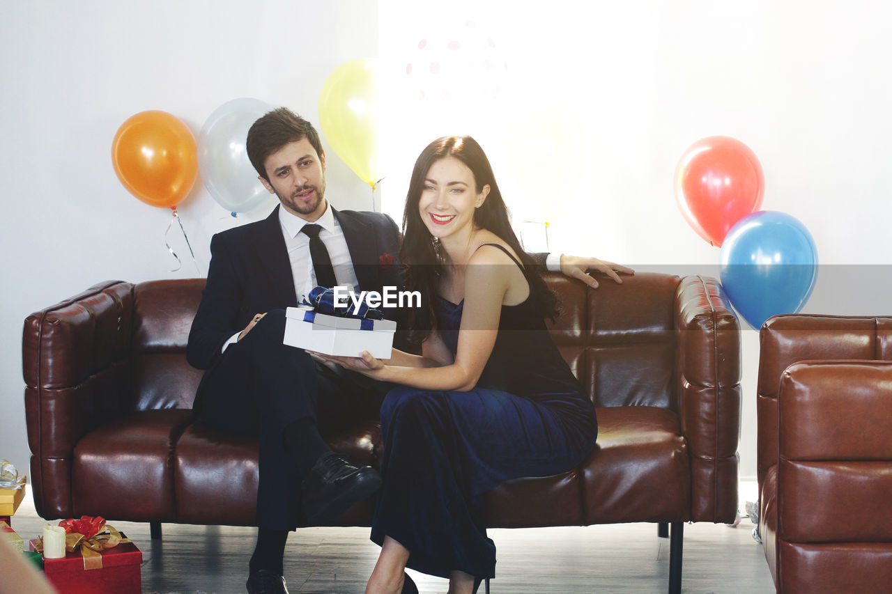 YOUNG COUPLE SITTING ON BALLOONS AT HOME