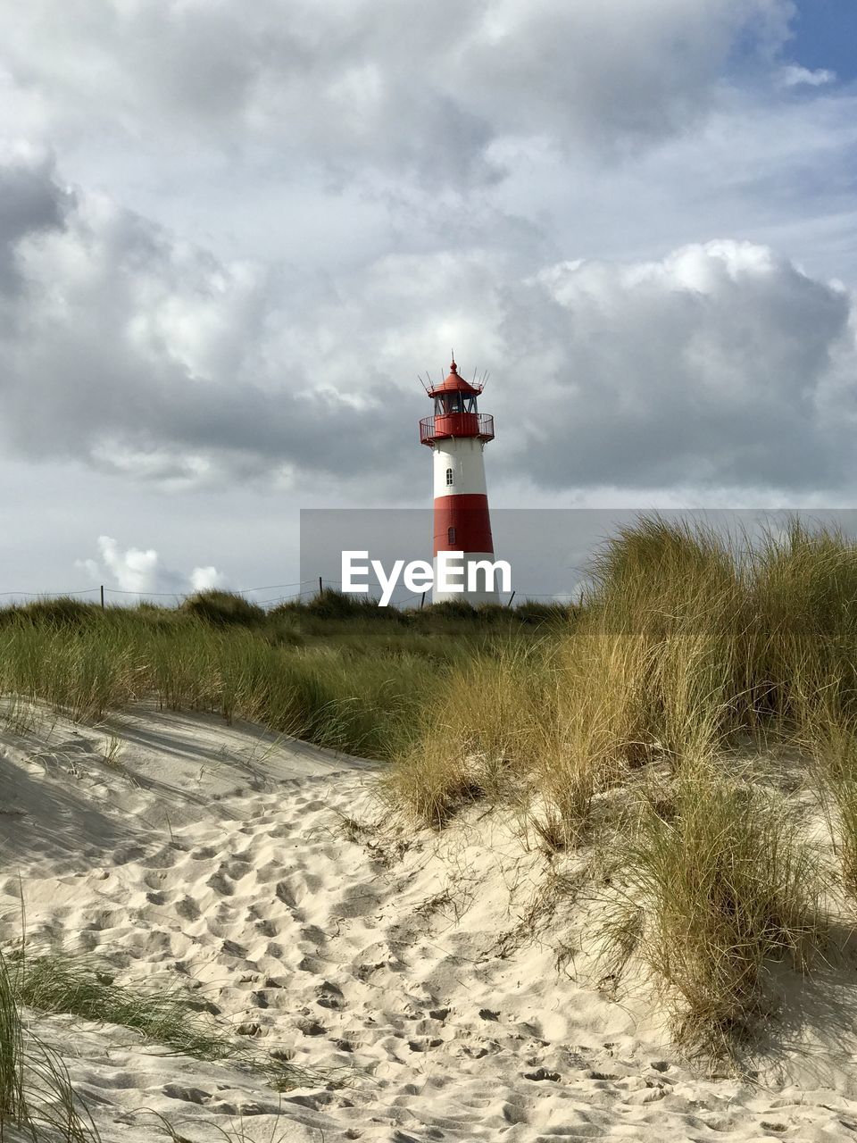 LIGHTHOUSE ON LAND BY BUILDING AGAINST SKY