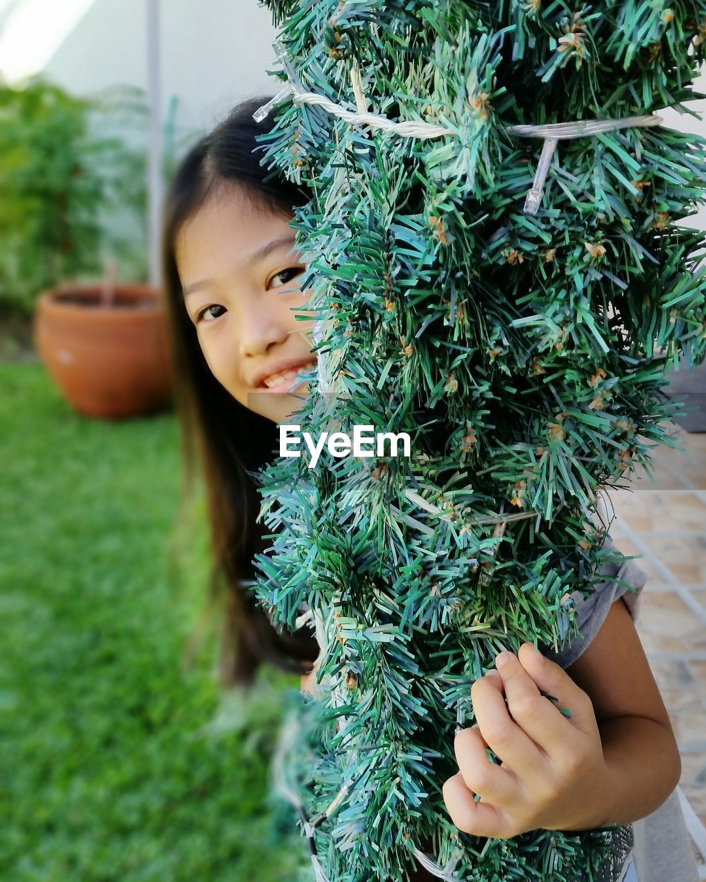 Close-up portrait of girl holding plant in yard