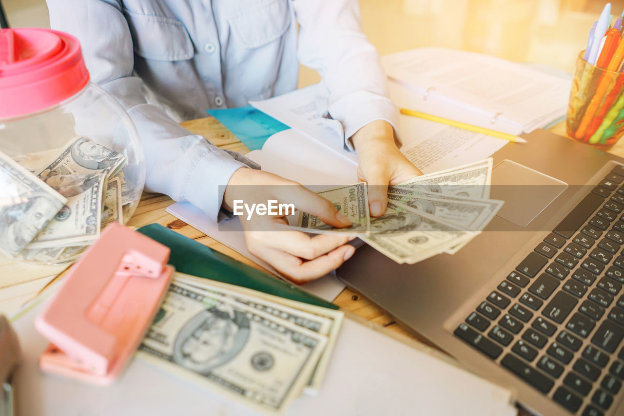 High angle view of businessman working with money and laptop on table