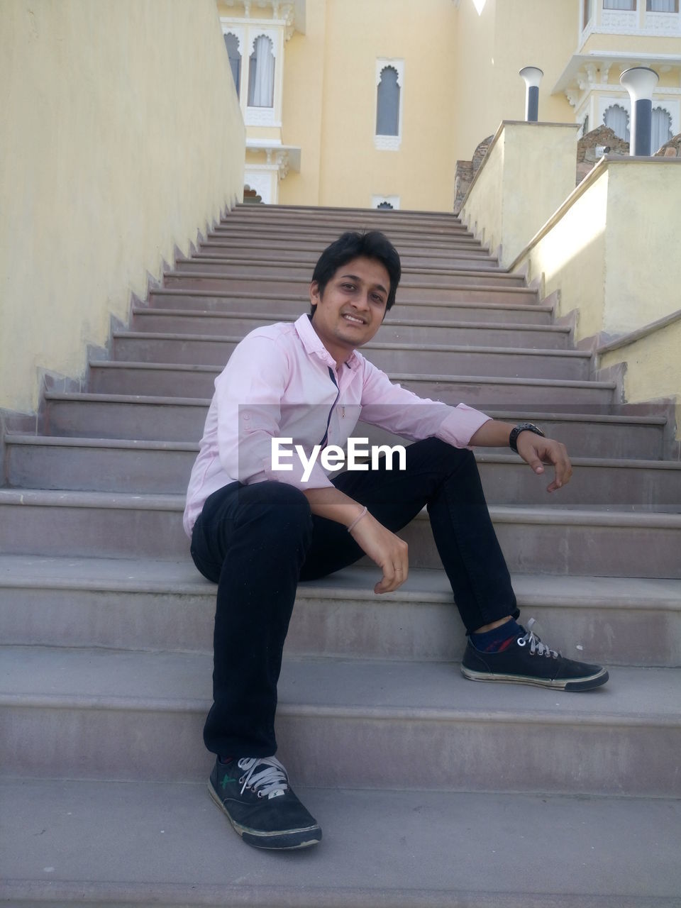 PORTRAIT OF SMILING YOUNG WOMAN SITTING ON STAIRS