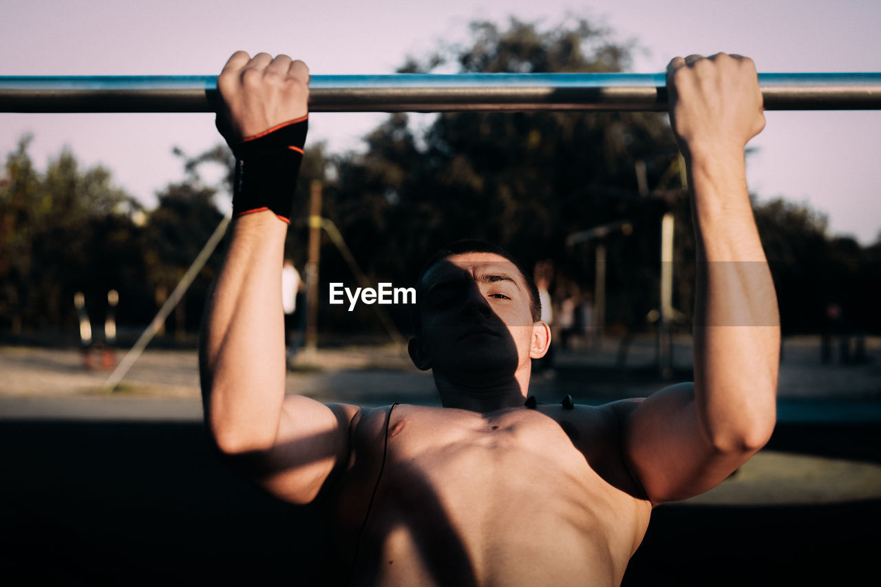 Shirtless man exercising at park