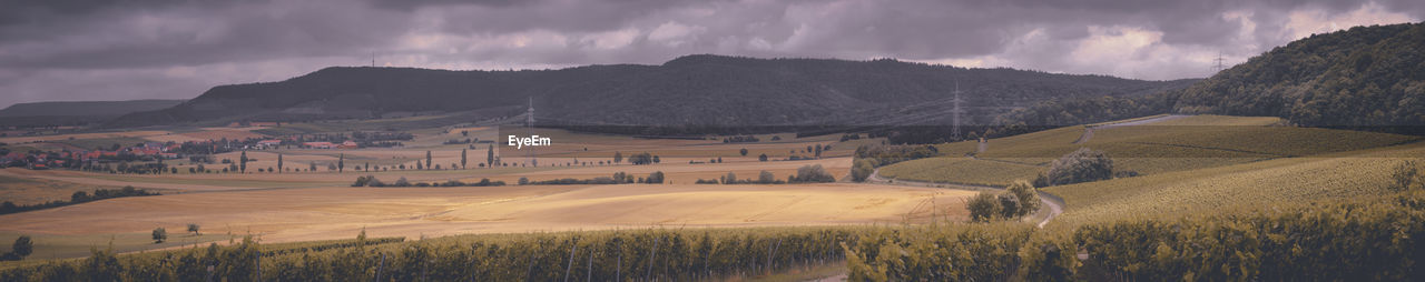 PANORAMIC VIEW OF FIELD AND MOUNTAINS AGAINST SKY