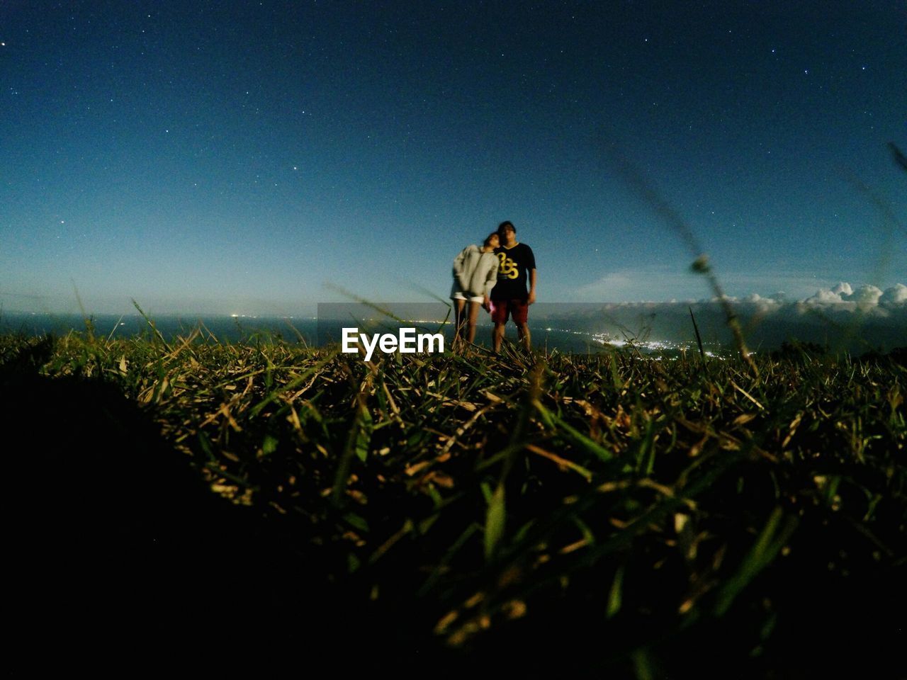 Low angle view of couple in field against sky at night