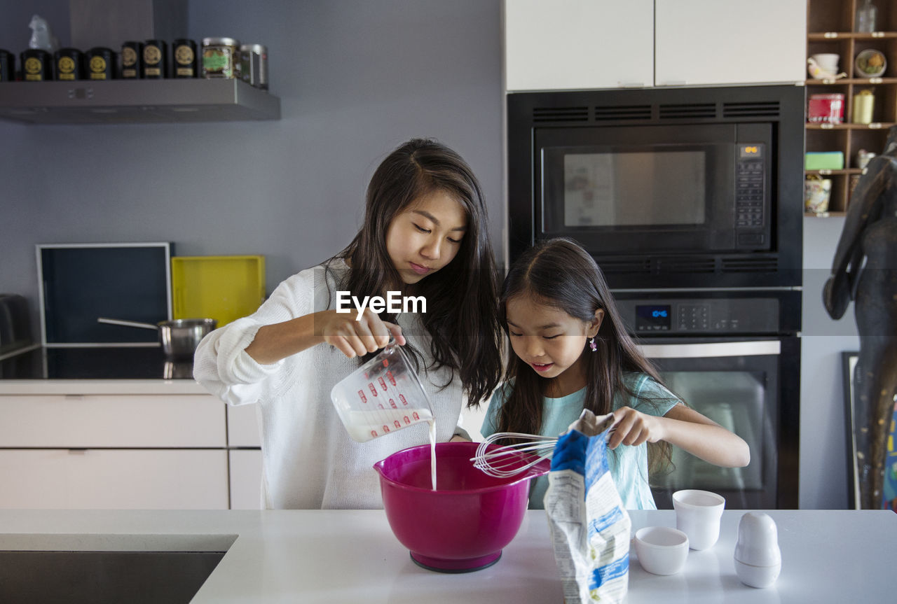Sisters preparing food in kitchen at home