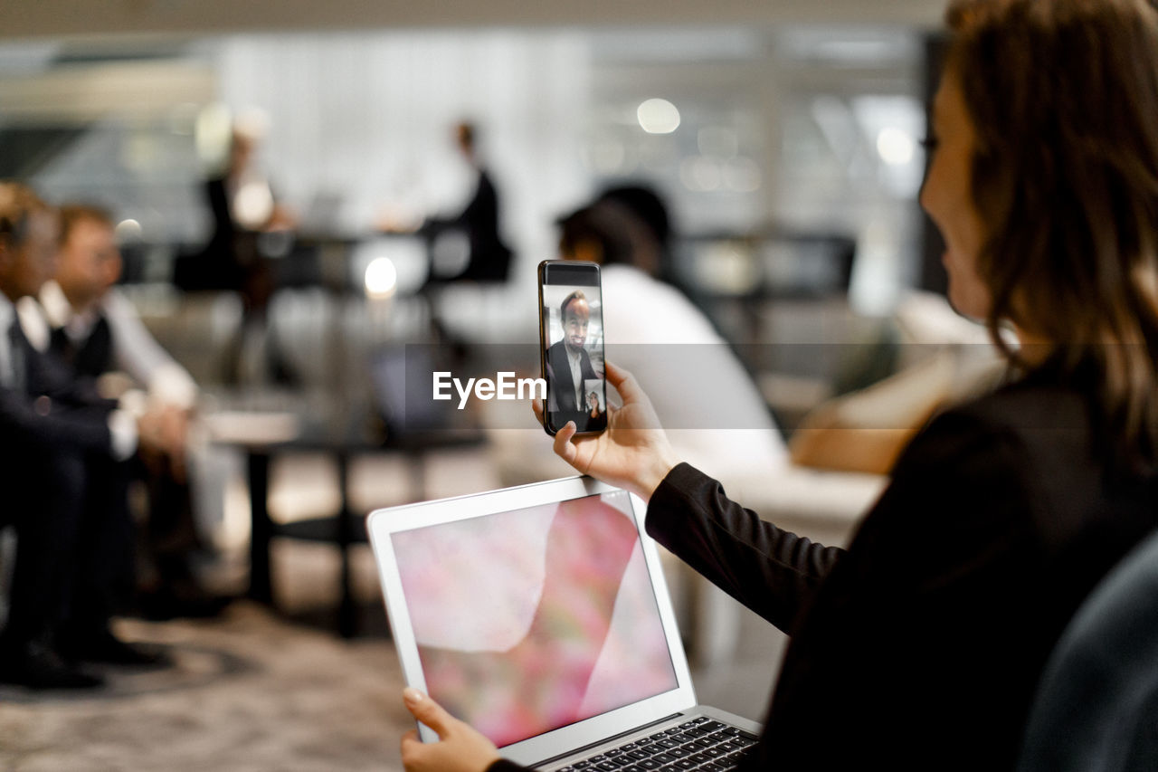 Businesswoman talking to colleague through video call on mobile phone in office