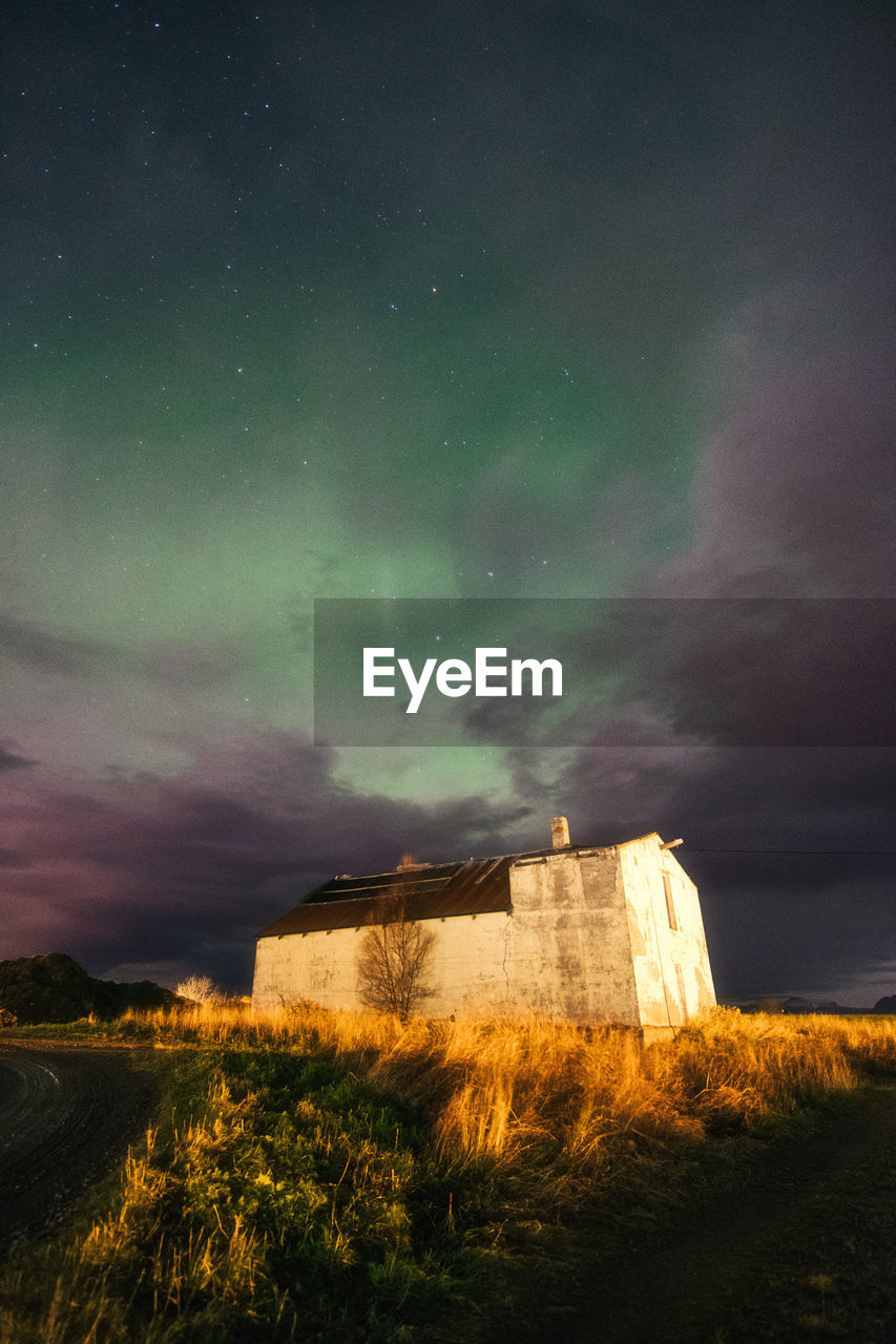 Faint northern lights over abandoned building at night