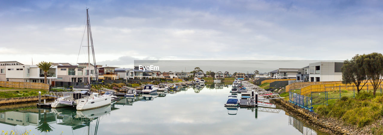 Sailboats moored at harbor against buildings in city