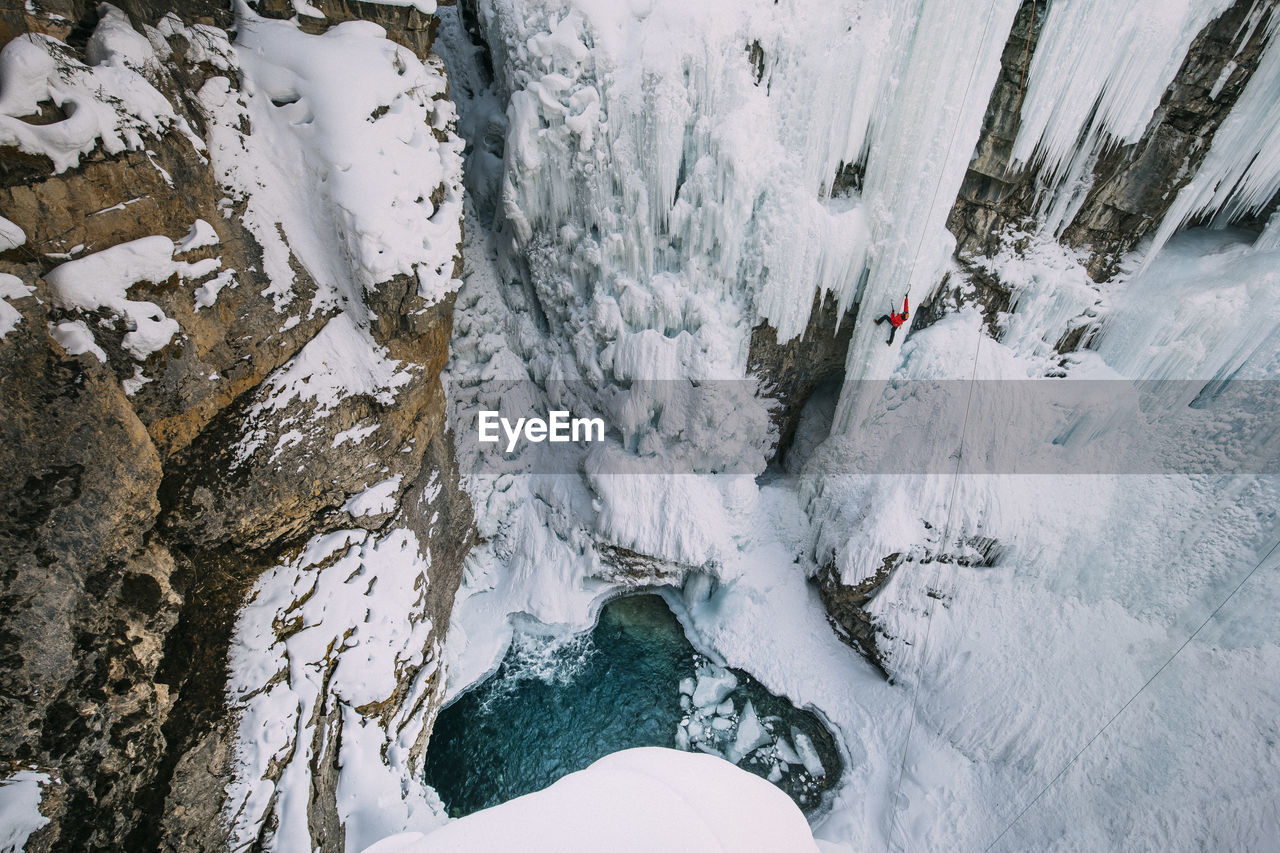 High angle view of woman climbing on snowcapped mountain during winter
