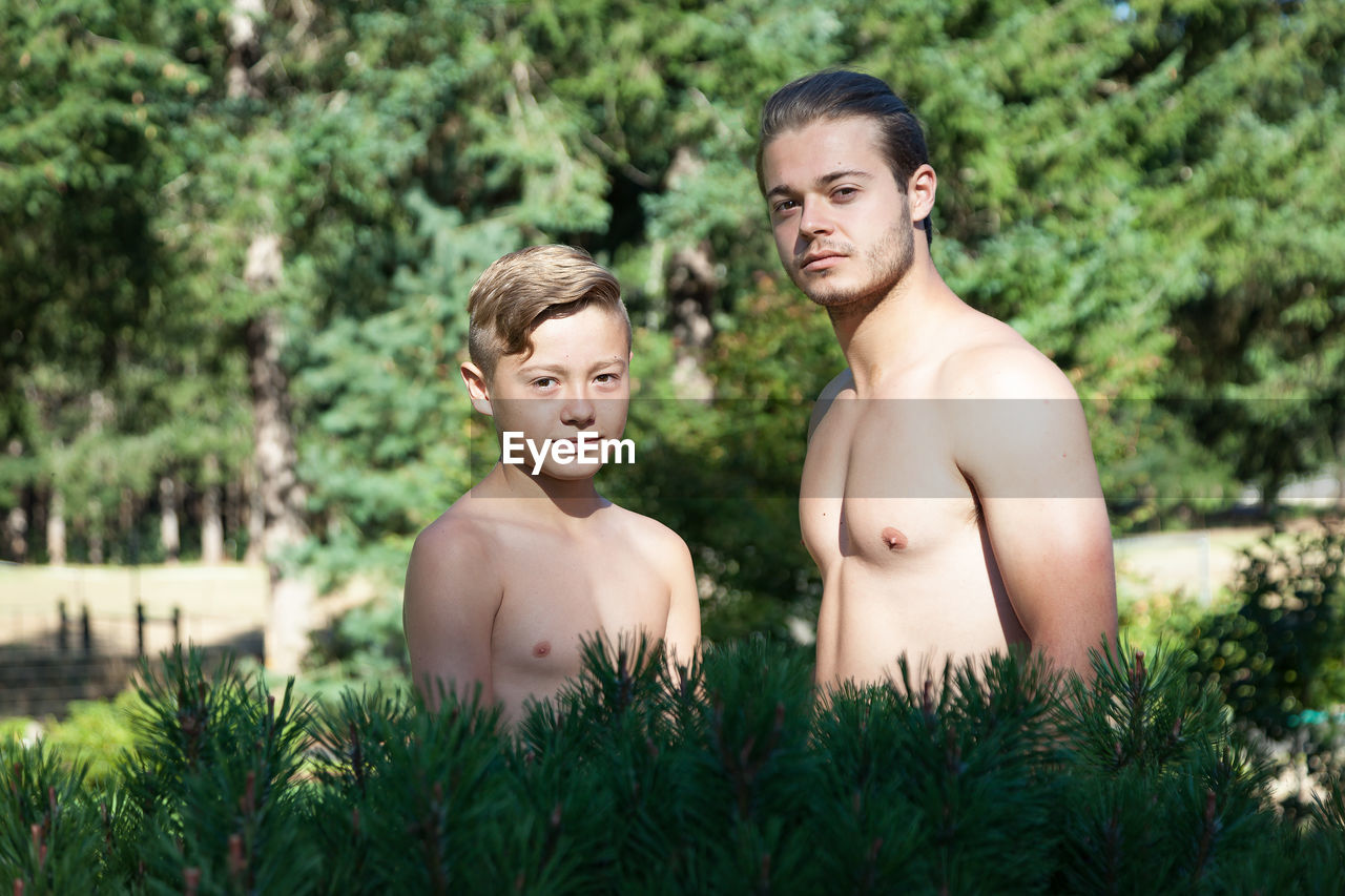 Portrait of shirtless brothers standing in park