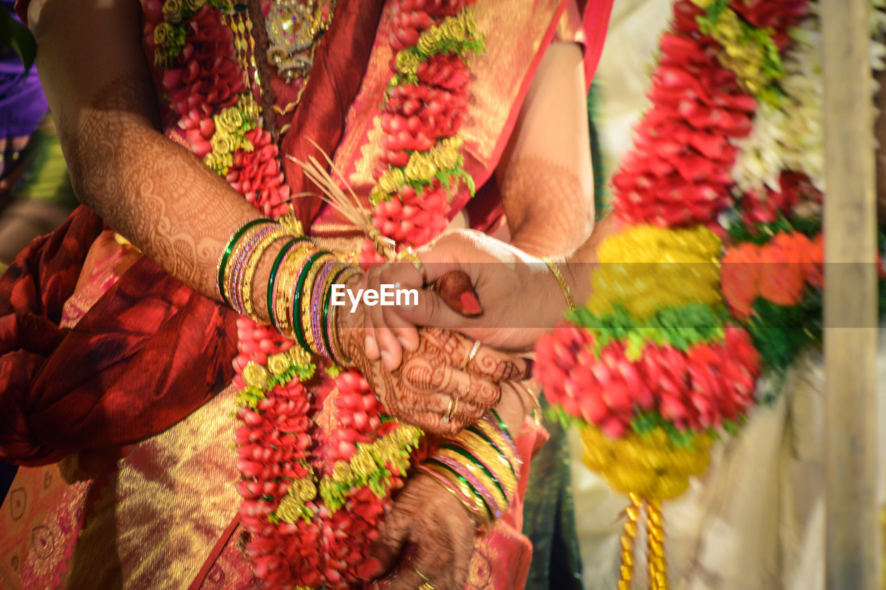 Cropped image of groom holding bride hand during wedding ceremony