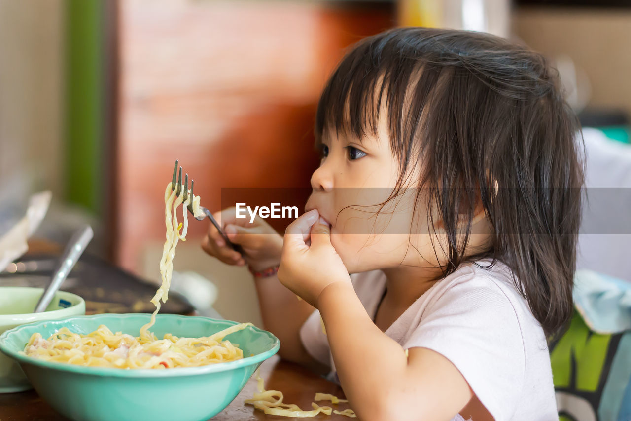 Cute baby girl eating noodles