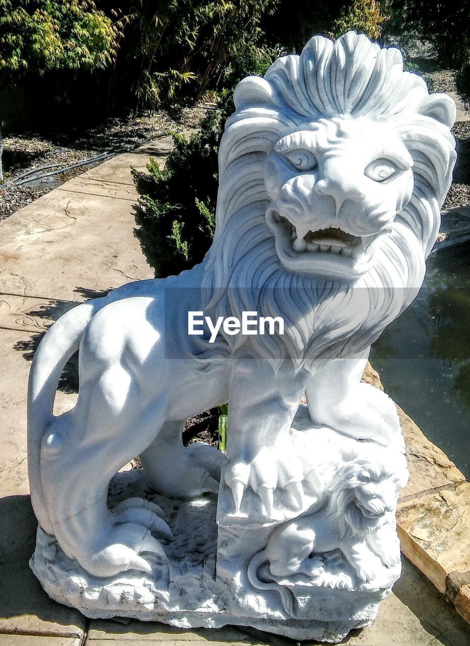 High angle view of white lion statue on footpath