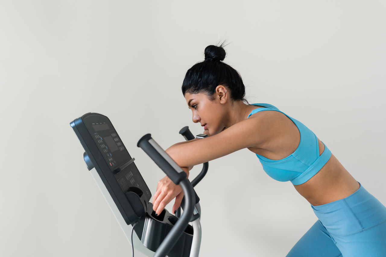 Young woman training at the gym using eliptical crosstrainer