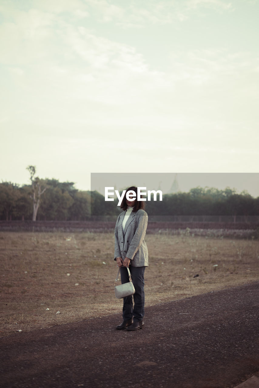 Rear view of woman walking on field against sky