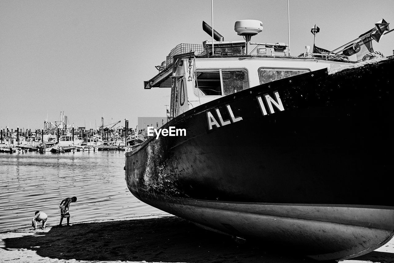 MAN ON BOAT MOORED AGAINST CLEAR SKY