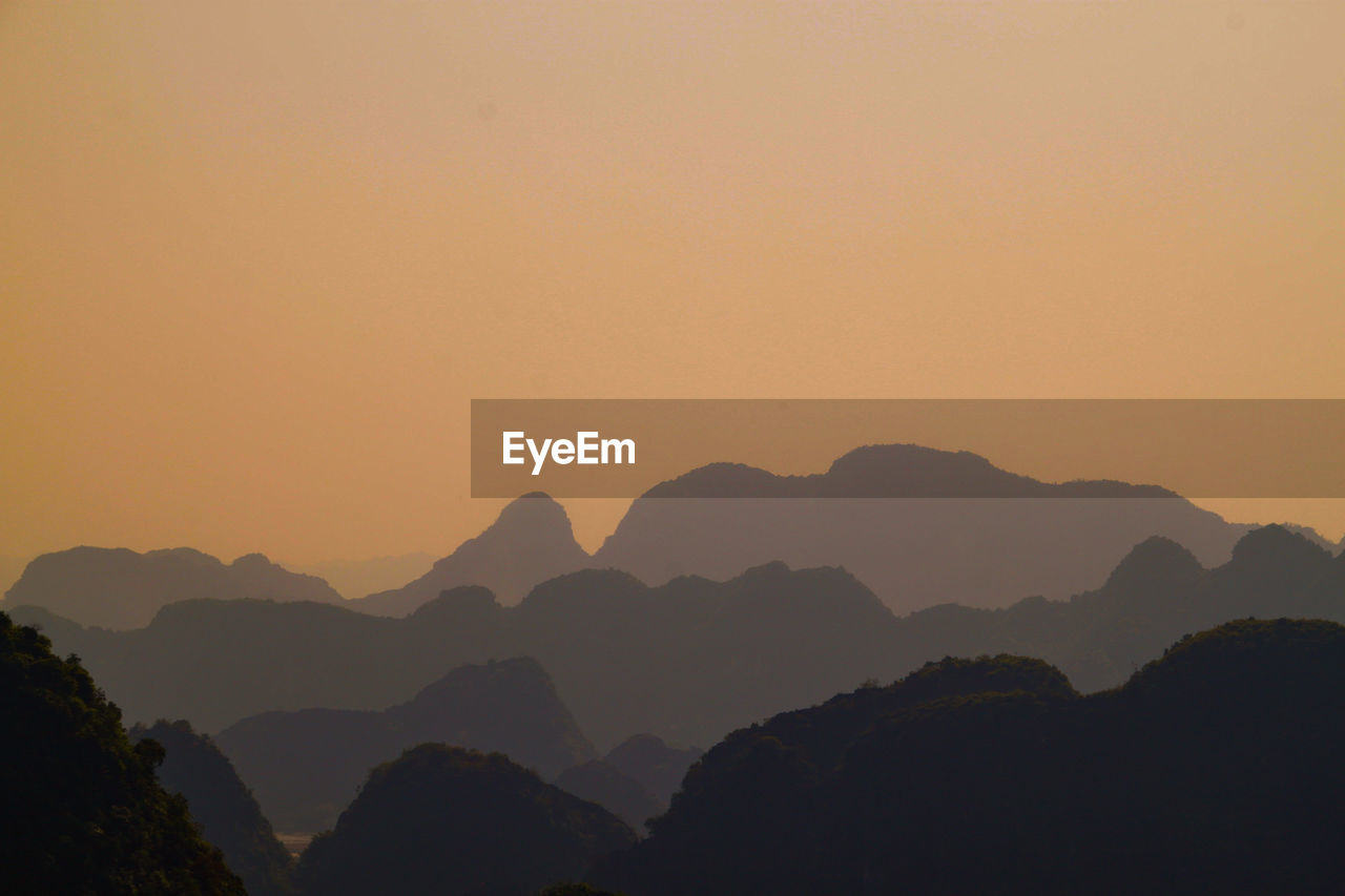 Scenic view of silhouette mountains against orange sky