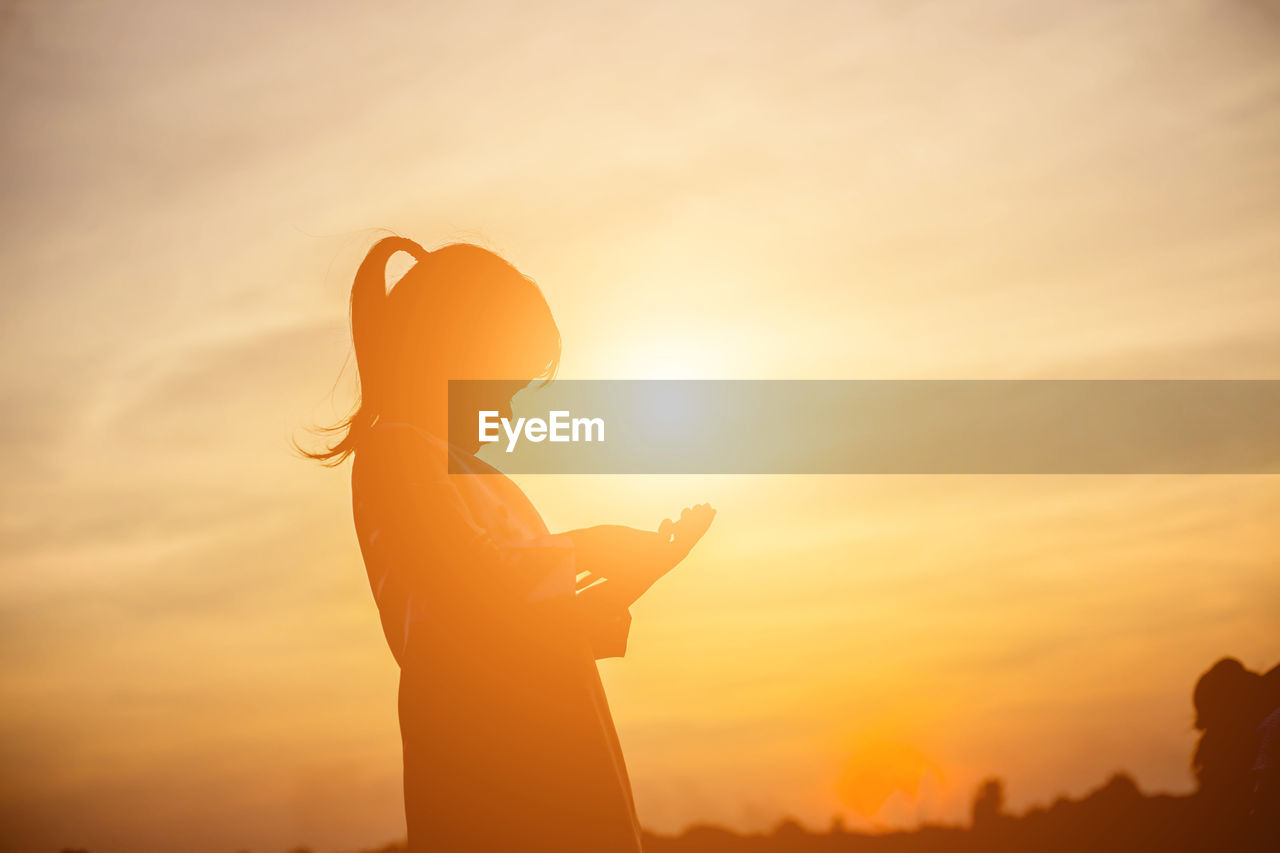 Silhouette man using smart phone against sky during sunset