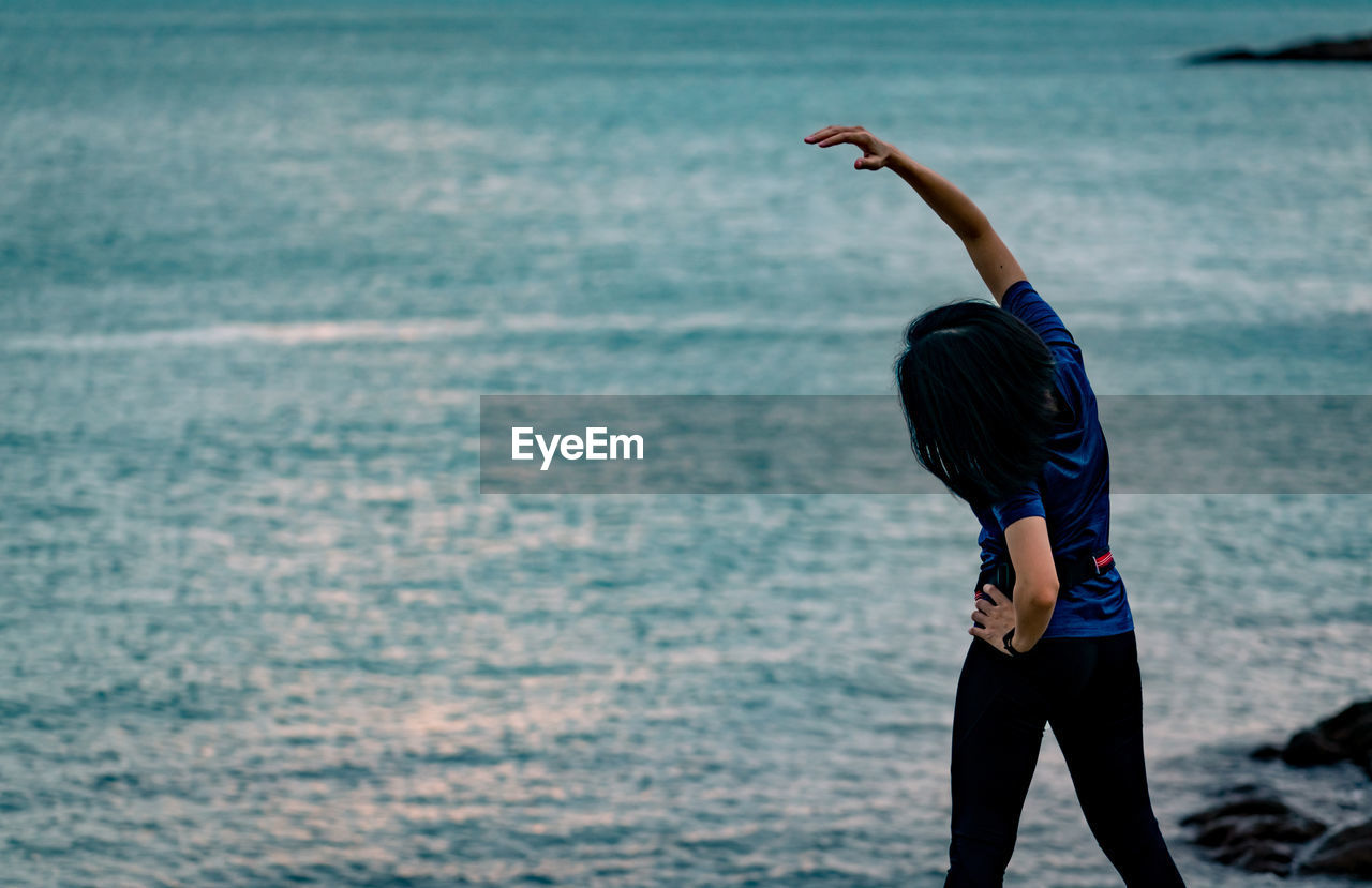 Rear view of woman standing at beach