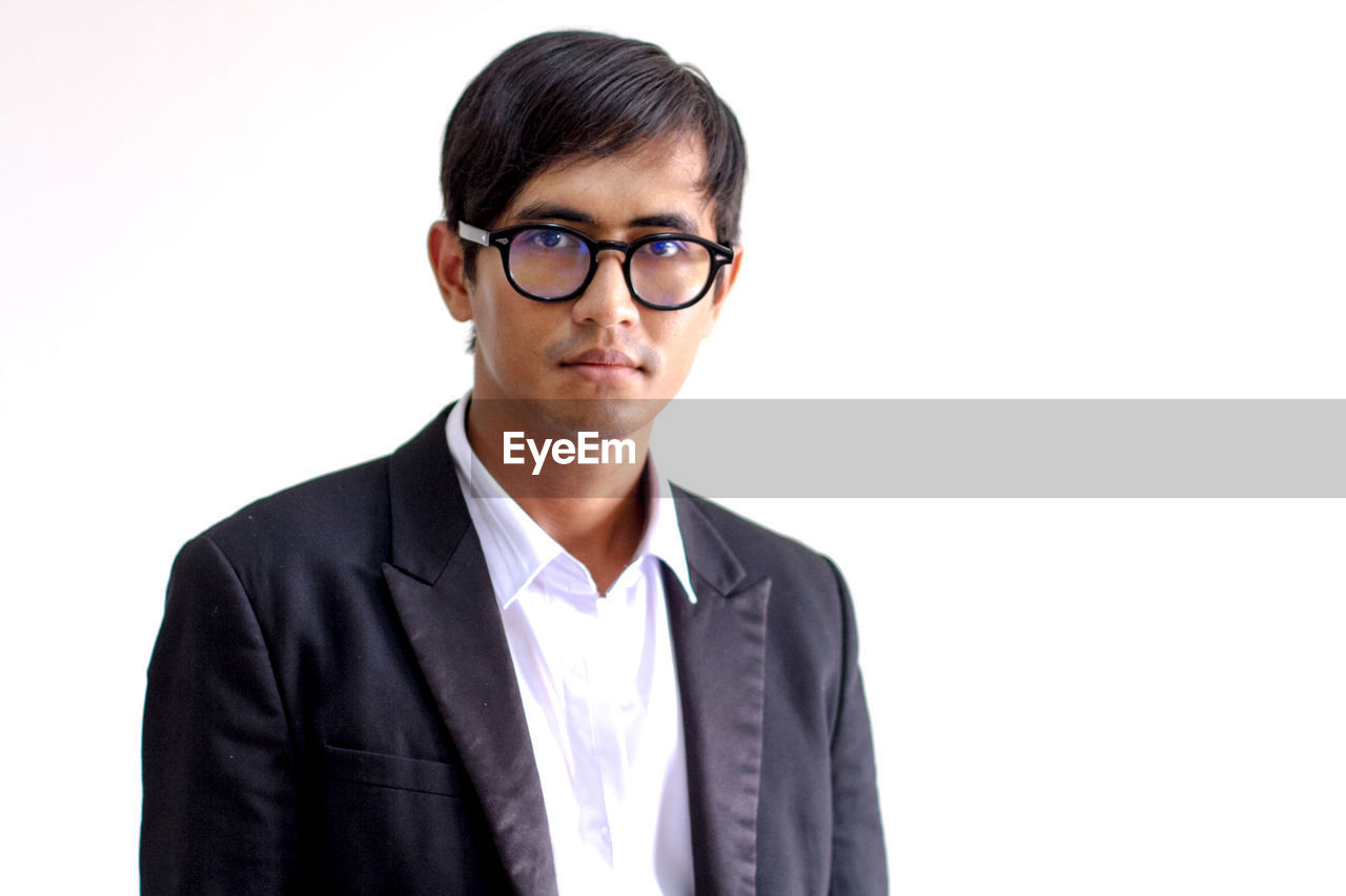 Portrait of businessman wearing eyeglasses against white background