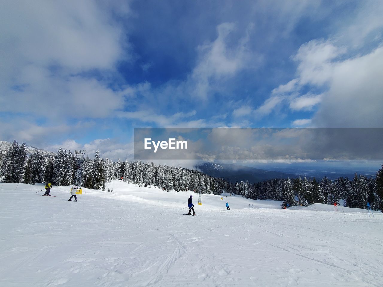 People skiing on snow covered mountain against sky