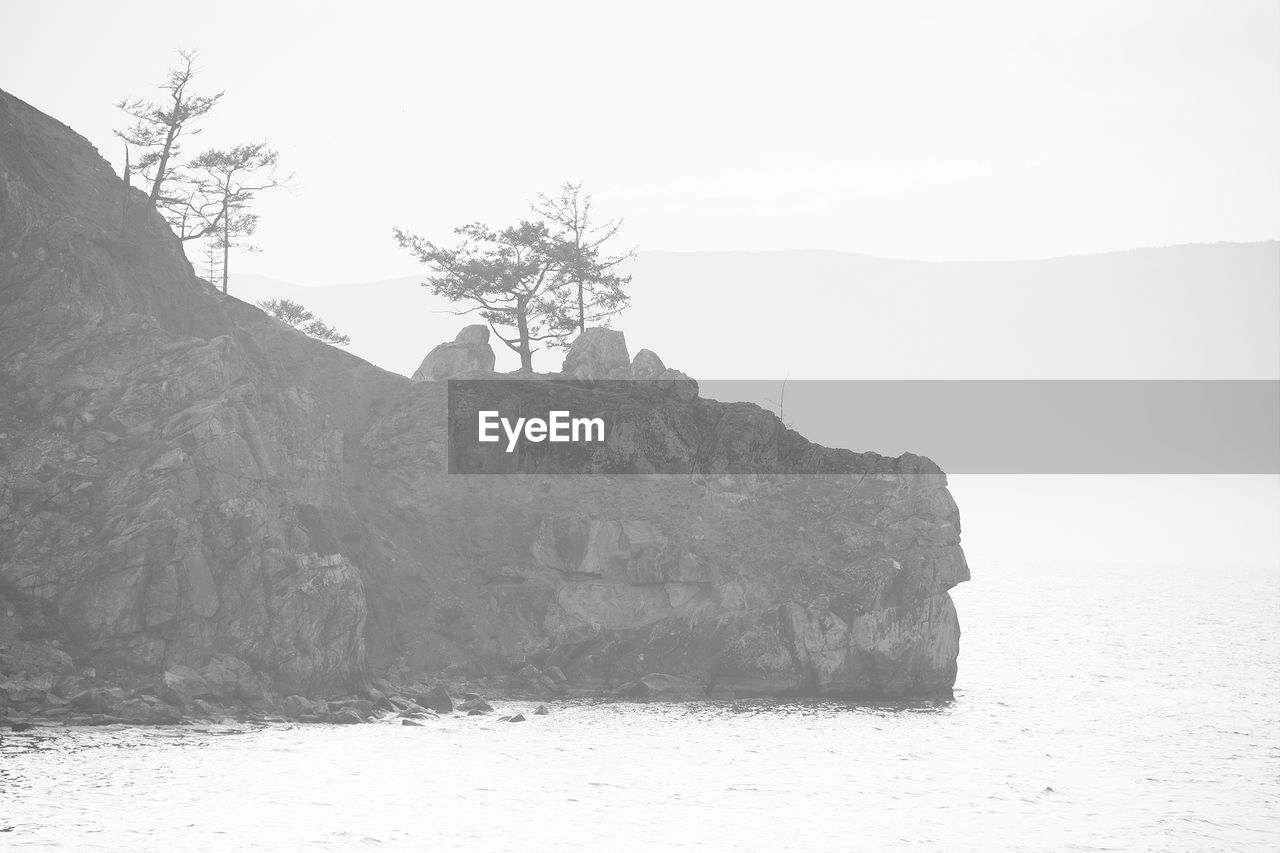 ROCK FORMATION ON SHORE AGAINST SKY